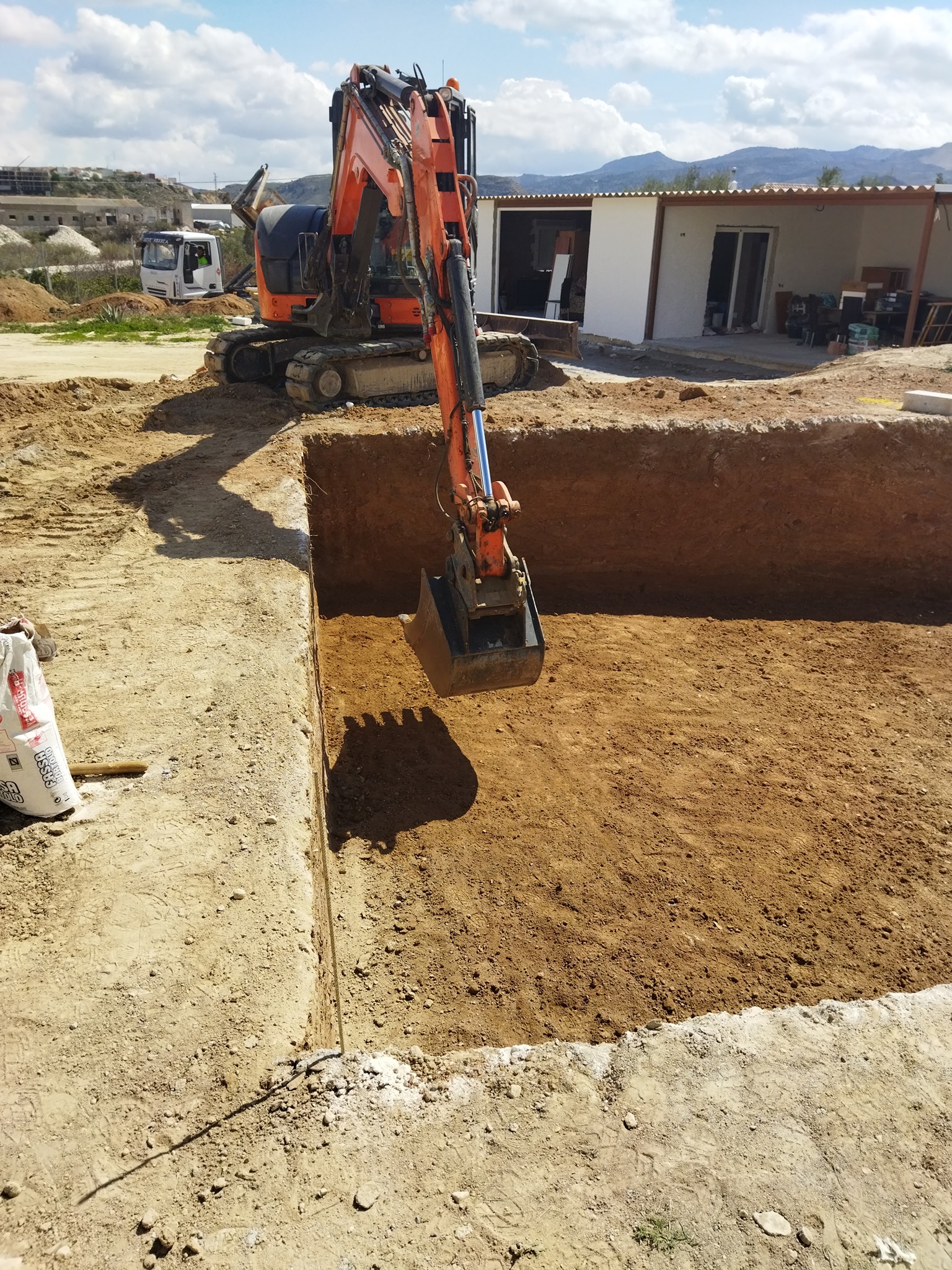 Excavadora Hitachi perfilando las paredes laterales de la piscina