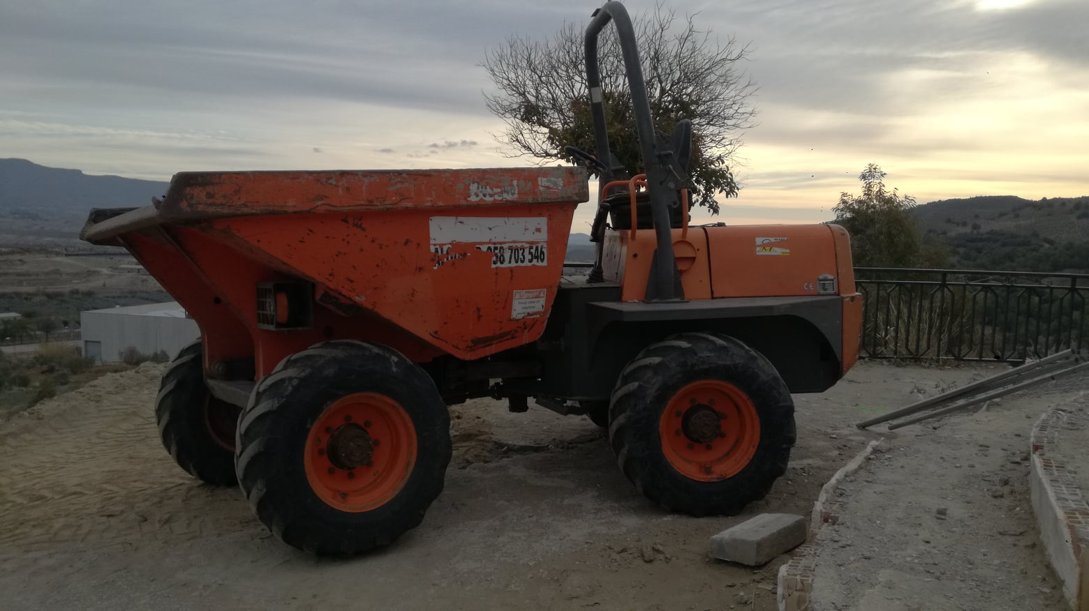 Dumper Ausa naranja al atardecer cargado con tierras del rebaje de Tíjola