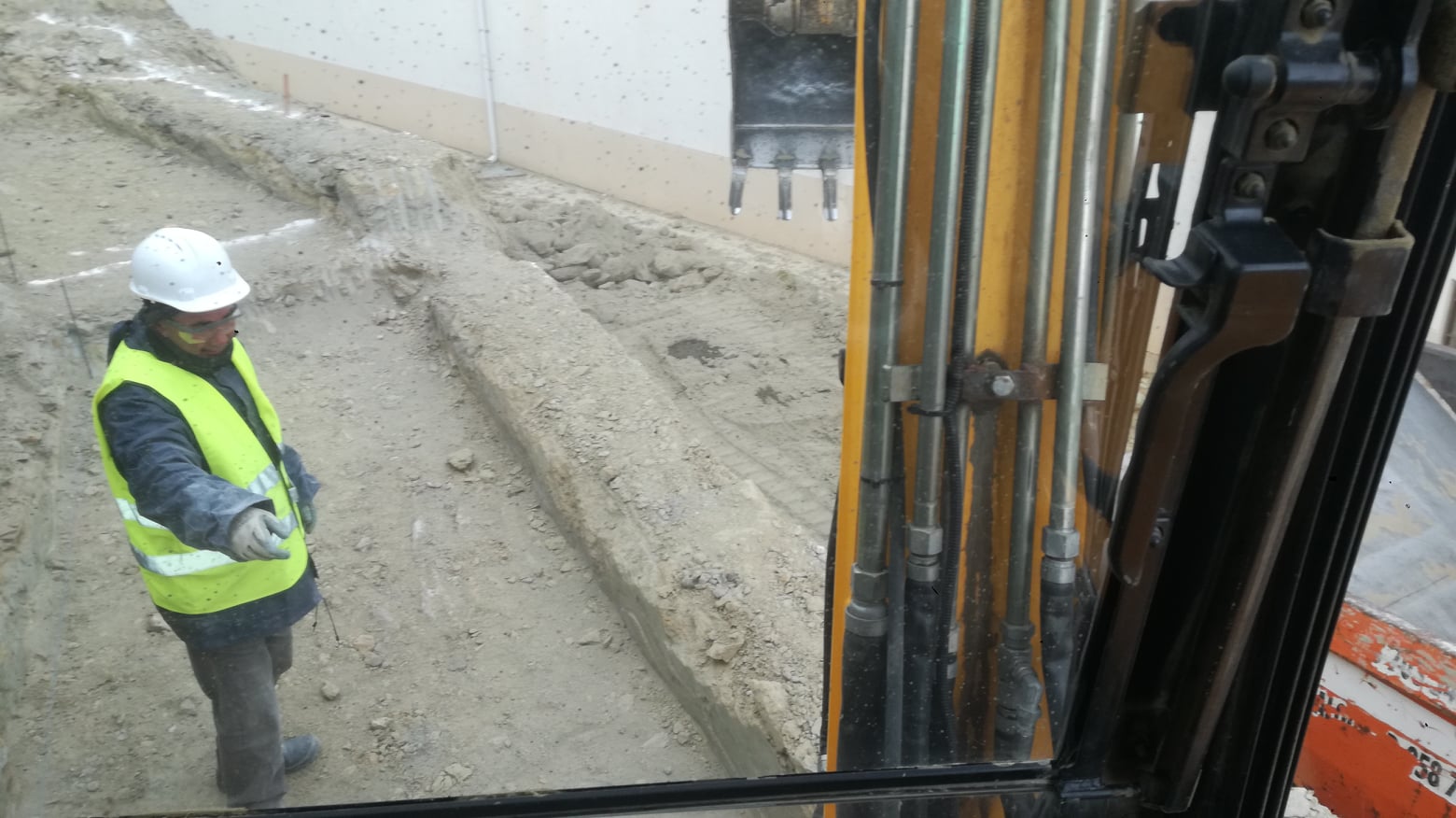 Operario con chaleco de seguridad junto al brazo hidráulico de la excavadora